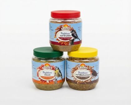 Drie potten vogelvoer pindakaas met verschillende smaken.